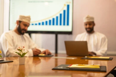 Studying statistical data, analyzing charts, conducting job interviews, concluding successful new business deals between businessmen, two Omani Arab Gulf men wearing traditional attire discussing their work tasks, expanding business fields, partnership in business and engineering projects.
