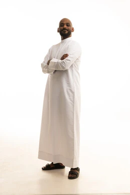 A portrait of a Saudi Arabian Gulf man wearing traditional attire, looking with expressions of joy, embodying masculinity and self-confidence, paying attention to external appearance and elegance, standing upright and steady, full-body image, white background.