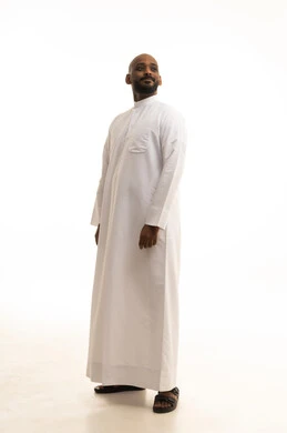الاهتمام بالمظهر الخارجي والأناقة، مفهوم الرجولة والثقة بالنفس،بورتريه لرجل عربي خليجي سعودي يرتدي الثوب التقليدي ينظر بتعابير السرور، الوقوف باستقامة وثبات، صورة الجسم بالطول الكامل، خلفية بيضاء