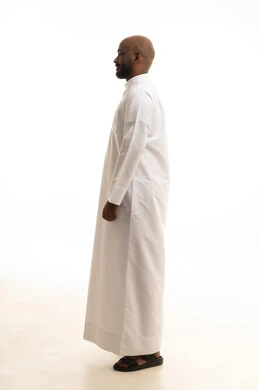 مفهوم الرجولة والثقة بالنفس، الاهتمام بالمظهر الخارجي والأناقة، بورتريه من الجانب لرجل عربي خليجي سعودي يرتدي الثوب التقليدي ينظر بتعابير السرور، الوقوف باستقامة وثبات، صورة الجسم بالطول الكامل، خلفية بيضاء