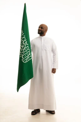 الفخر و الاعتزاز بالانتماء للمملكة, يوم العلم 11مارس، الاحتفال باليوم الوطني 8 ربيع الأول, ذكرى العيد الوطني السعودي, بورتريه لرجل عربي سعودي خليجي مبتسم يرتدي الثوب التقليدي يحمل بيده علم السعودية , خلفية بيضاء