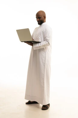 إستخدام الحاسوب المحمول لإنجاز المهام، عقد إجتماع عمل عبر الإنترنت، تصفح برامج التواصل الاجتماعي, بورتريه لرجل عربي خليجي سعودي يرتدي الثوب التقليدي يستخدم جهاز اللابتوب، تطور التكنولوجيا والأجهزة التقنية، خلفية بيضاء