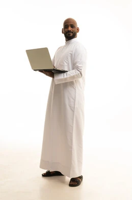 Browsing social media, holding a business meeting online, using a laptop to complete tasks, a portrait of an Arab Gulf Saudi man wearing traditional attire using a laptop, the evolution of technology and technical devices, white background.