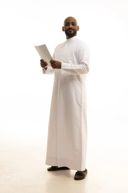 Preparing work-related reports, expressions of thought and focus, careful reading of notes, a portrait of a Saudi Arabian Gulf man wearing traditional attire holding a set of documents and white papers, reviewing and following up on plans and projects with gestures of happiness and joy, white background.