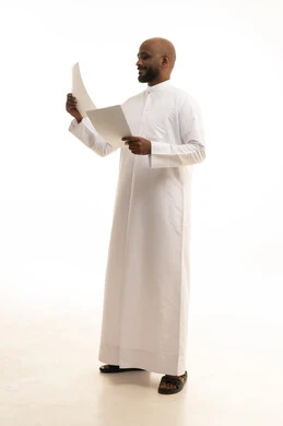 Expressions of thinking and concentration, scrutinizing the reading of notes, preparing work-related reports, a portrait of a Saudi Arabian Gulf man wearing traditional attire holding a set of documents and white papers in his hand, reviewing and following up on plans and projects with gestures of happiness and joy, white background.