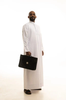 Attention to appearance and elegance, the concept of business and project management, walking and going somewhere, a portrait of a smiling Arab Gulf Saudi businessman wearing traditional attire holding a black leather bag in his hand, looking with gestures of cheerfulness and joy, full-body image, white background.