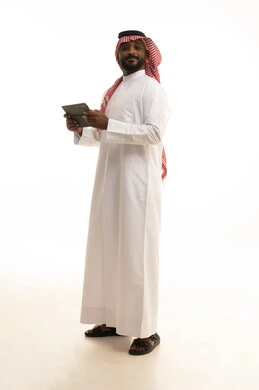Chatting with friends and relatives via the tablet, using a modern and advanced technological device, gestures of joy and happiness, an Arab Gulf Saudi man wearing traditional attire and a ghutrah holding the tablet in his hand, white background.