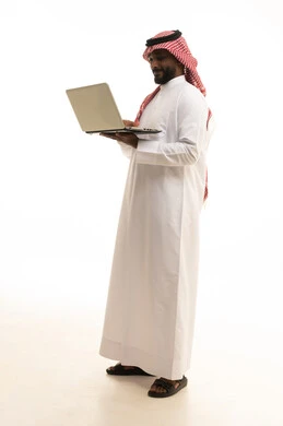 إستخدام الحاسوب المحمول لإنجاز المهام، عقد إجتماع عمل عبر الإنترنت، تصفح برامج التواصل الاجتماعي, بورتريه لرجل عربي خليجي سعودي يرتدي الثوب التقليدي والشماغ يحمل جهاز اللابتوب ، تطور التكنولوجيا والأجهزة التقنية، خلفية بيضاء