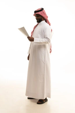 Expressions of thinking and focus, scrutinizing notes, preparing work reports, a portrait of a Saudi Arabian Gulf man wearing traditional attire and a ghutrah holding a set of documents and white papers, reviewing and following up on plans and projects with gestures of happiness and joy, white background.