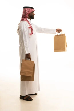 Reliable shipping and delivery process, fast delivery services, ordering and receiving delivery, portrait of an Arab Saudi Gulf man wearing traditional attire and a ghutrah working in delivering orders and goods to customers, online shopping and online orders, white background.