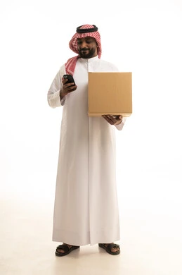 التسوق الالكتروني وطلبات اونلاين,  دمج التقنيات الحديثة فى الحياه اليوميه ، عملية شحن وتوصيل موثوقه, خدمات التوصيل السريع, طلب وإستلام الدليفري, بورتريه لرجل عربي سعودي خليجي يرتدي الزى التقليدي والشماغ يمسك بيده الجوال يعمل في توصيل الطلبات والبضائع للزبائن, خلفيه بيضاء