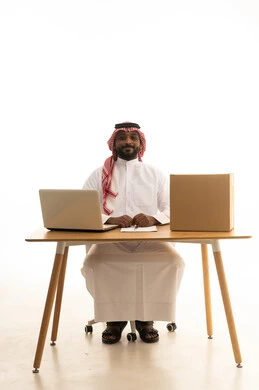 تدوين الملاحظات الهامه ، مفهوم التسويق الإلكتروني وطلبات الاونلاين ، مهن ووظائف سعودية ، بورتريه لرجل عربي خليجي سعودي يرتدي الزى التقليدي والشماغ يستخدم جهاز الحاسوب المحمول وامامه اكياس التسوق الورقية ، تصفح وسائل التواصل الاجتماعي، إستخدام اجهزة تقنية حديثة ، العمل عن بعد ،خلفية بيضاء