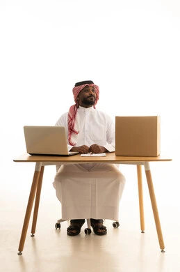 Taking important notes, the concept of electronic marketing and online orders, Saudi professions and jobs, a portrait of a Saudi Gulf Arab man wearing traditional attire and a ghutrah using a laptop with shopping bags in front of him, browsing social media, using modern technological devices, working remotely, white background.