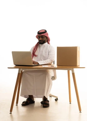 مفهوم التسويق الإلكتروني وطلبات الاونلاين ، عقد إجتماع عمل عبر اللابتوب ، مهن ووظائف سعودية ، بورتريه لرجل عربي خليجي سعودي يرتدي الزى التقليدي والشماغ يستخدم جهاز الحاسوب المحمول وامامه اكياس التسوق الورقية ، تصفح وسائل التواصل الاجتماعي، إستخدام اجهزة تقنية حديثة ، العمل عن بعد ،خلفية بيضاء