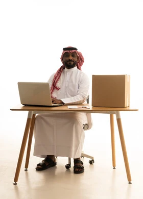 A business meeting held via laptop, the concept of electronic marketing and online orders, Saudi professions and jobs, a portrait of an Arab Gulf Saudi man wearing traditional attire and a ghutrah using a laptop with shopping bags in front of him, browsing social media, using modern technological devices, remote work, white background.