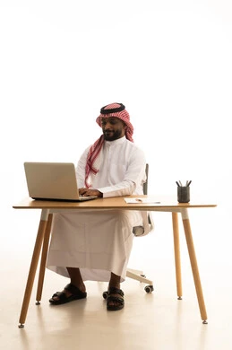 عقد إجتماع عمل عبر اللابتوب ، مفهوم التسويق الإلكتروني ، مهن ووظائف سعودية ، بورتريه لرجل عربي خليجي سعودي يرتدي الزى التقليدي والشماغ يستخدم جهاز الحاسوب المحمول ، تصفح وسائل التواصل الاجتماعي، إستخدام اجهزة تقنية حديثة ، العمل عن بعد ،خلفية بيضاء