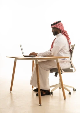 مهن ووظائف سعودية ، عقد إجتماع عمل عبر اللابتوب ، بورتريه لرجل عربي خليجي سعودي يرتدي الزى التقليدي والشماغ يستخدم جهاز الحاسوب المحمول ، تصفح وسائل التواصل الاجتماعي، إستخدام اجهزة تقنية حديثة ، العمل عن بعد ،خلفية بيضاء