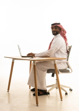 بورتريه لرجل عربي خليجي سعودي يرتدي الزى التقليدي والشماغ يستخدم جهاز الحاسوب المحمول ، تصفح وسائل التواصل الاجتماعي، إستخدام اجهزة تقنية حديثة ، العمل عن بعد ،مفهوم التسويق الإلكتروني ، مهن ووظائف سعودية ، عقد إجتماع عمل عبر اللابتوب ، خلفية بيضاء