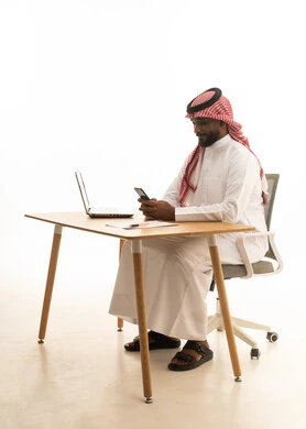 إستخدام اجهزة تقنية حديثة ، العمل عن بعد ،عرض شاشة سوداء فارغة، عقد إجتماع عمل عبر اللابتوب ، بورتريه لرجل عربي خليجي سعودي يرتدي الزى التقليدي والشماغ يستخدم جهاز الحاسوب المحمول ، تصفح وسائل التواصل الاجتماعي، خلفية بيضاء