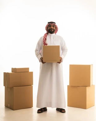 Cardboard boxes and containers, home arrangement and organization, a portrait of a Saudi Arabian Gulf man wearing traditional attire and a ghutrah, transporting boxes of household items, owning a new home and family stability, modern housing and ownership, full-body image, white background.