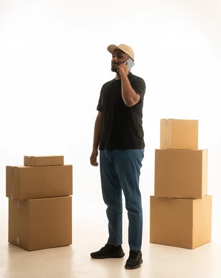 The use of technology and modern techniques, arranging and organizing the home, a portrait of an Arab Gulf Saudi man wearing casual attire delivering boxes of household items while holding a mobile phone, owning a new residence and family stability, modern housing and ownership, full-body image, white background.