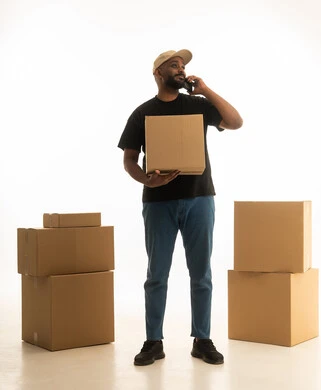 اجراء مكالمه هاتفيه ،ترتيب وتنظيم المنزل، بورتريه لرجل عربي خليجي سعودي يرتدي الزى الكاجوال يقوم  بتوصيل صناديق الأغراض المنزلية يمسك بيده الجوال ، امتلاك سكن جديد والاستقرار العائلي، اسكان وتمليك حديث ، صورة الجسم بالطول الكامل، خلفية بيضاء