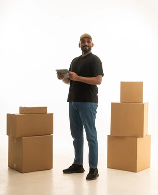 The use of modern devices and technologies, browsing social media, home delivery of orders, organizing and arranging the home, a portrait of a Saudi Arabian Gulf man wearing casual attire delivering boxes of household items while holding a tablet, owning a new home and family stability, modern housing and ownership, full-body image, white background.