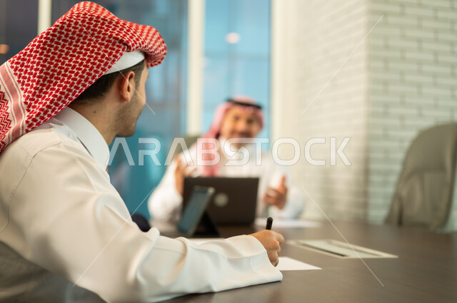 تبادل الخبرات والمعلومات لتحقيق الاهداف, استخدام الحاسب والتقنية في مجال الاعمال، بيئة العمل المريحة في الشركات السعودية، الحوار و النقاش بين الزملاء، موظفان عربيان خليجيان سعوديان يقومان بالعمل ومشاركة الأفكار داخل مقر الشركة