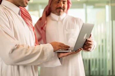 تبادل الخبرات والمعلومات لتحقيق الاهداف, استخدام الحاسب والتقنية في مجال الاعمال، بيئة العمل المريحة في الشركات السعودية، الحوار و النقاش بين الزملاء، موظفان عربيان خليجيان سعوديان يقومان بالعمل ومشاركة الأفكار داخل مقر الشركة