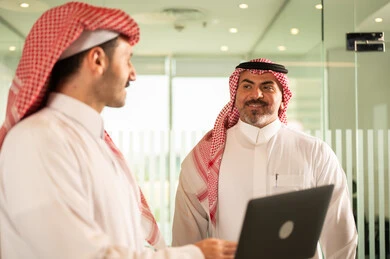 تبادل الخبرات والمعلومات لتحقيق الاهداف, استخدام الحاسب والتقنية في مجال الاعمال، بيئة العمل المريحة في الشركات السعودية، الحوار و النقاش بين الزملاء، موظفان عربيان خليجيان سعوديان يقومان بالعمل ومشاركة الأفكار داخل مقر الشركة