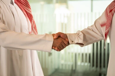 صفقات عمل جديدة ناجحة بين رجال الأعمال، الاتفاق والشراكة على الأعمال والمشاريع التجارية، تعارف وصداقات وبناء علاقات اجتماعية، صورة مقربة لرجلين عربيين خليجيين سعوديين يقومان بمصافحة بعضهما داخل مقر الشركة 