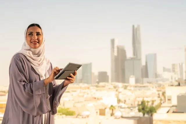 جهاز تقني حديث و متطور،تصفح الانترنت و مواقع التواصل الاجتماعي عبر جهاز التابليت ،سيدة عربية خليجية سعودية ترتدي العباءة تقوم باستخدام الجهاز اللوحي بايماءات السعادة والسرور،الخروج في الهواء الطلق،التواصل مع الاهل و الاصدقاء