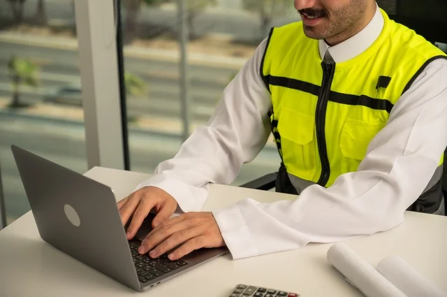   مهارة وسرعة الأيدي في الكتابة، تدقيق ومراجعة الخطط الهندسية, لإكمال رسم مخطوطات البناء دمج التكنولوجيا مع الهندسة ،مفهوم الهندسة والإنشاءات، مهندس عربي خليجي سعودي يرتدي الثوب التقليدي والسترة الخاصة بالعمل يجلس على المكتب ويعمل على الحاسوب المحمول 