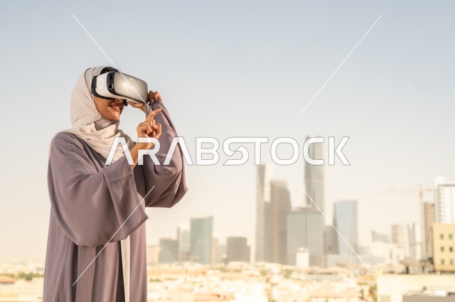 الاستمتاع في قضاء اوقات ترفيهية، تقنيات حديثة الكترونية وأجهزة تكنولوجية، التفاعل ومحاكاة العالم الافتراضي الخيالي, امرأة عربية خليجية سعودية محجبة تضع نظارات الفي ار, قضاء وقت ممتع خارج المنزل