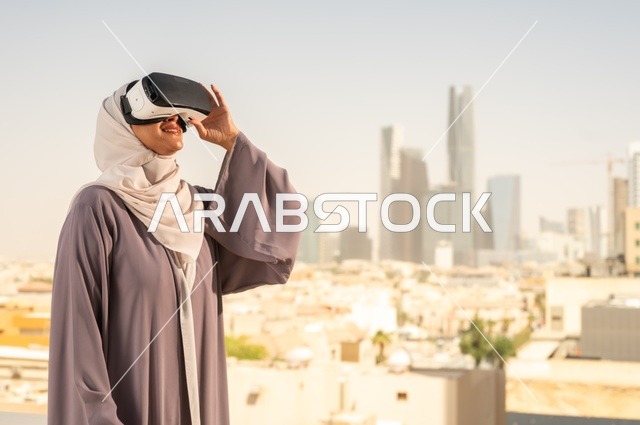 الاستمتاع في قضاء اوقات ترفيهية، تقنيات حديثة الكترونية وأجهزة تكنولوجية، التفاعل ومحاكاة العالم الافتراضي الخيالي, امرأة عربية خليجية سعودية محجبة تضع نظارات الفي ار, قضاء وقت ممتع خارج المنزل