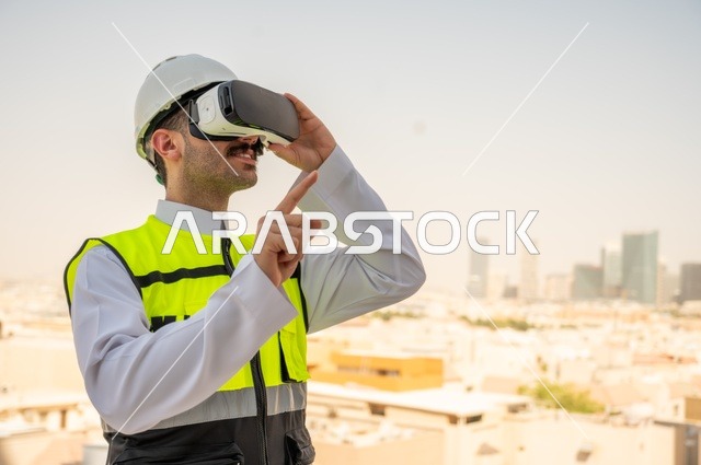  تقدم وتطور المباني في المملكة العربية السعودية، مفهوم أدارة المشاريع الهندسية، صورة جانبية لمهندس عربي خليجي سعودي يرتدي الثوب التقليدي والسترة الخاصة وخوذة الحماية ينظر في نظارة واقع افتراضي ثلاثية الأبعاد، خلفية أبراج وناطحات سحاب 