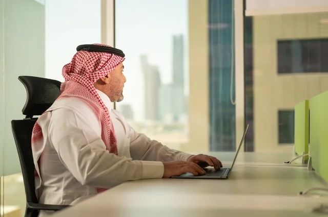 إدارة شؤون الأعمال وتنظيمها، استخدام جهاز تقني حديث ومتطور، مهنة ووظيفة ادارية مكتبية، موظف عربي خليجي سعودي يرتدي الثوب التقليدي يقوم بالعمل على الحاسوب المحمول داخل المكتب، الشركات والمكاتب في المملكة العربية السعودية، خلفية أبراج الرياض إدارة شؤون الأعمال وتنظيمها، استخدام جهاز تقني حديث ومتطور، مهنة ووظيفة ادارية مكتبية، موظف عربي خليجي سعودي يرتدي الثوب التقليدي يقوم بالعمل على الحاسوب المحمول داخل المكتب، الشركات والمكاتب في المملكة العربية السعودية، خلفية أبراج الرياض