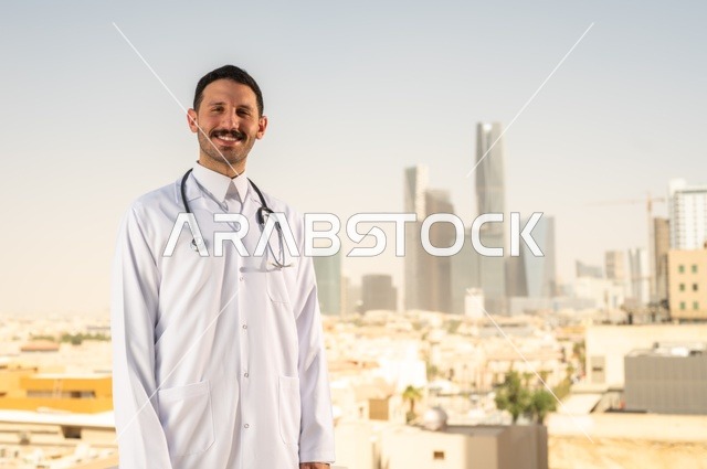 مفهوم الفحص الطبي، العمل في القطاع الصحي، تقديم الخدمات العلاجية للمرضى, طبيب عربي خليجي سعودي يرتدي الثوب التقليدي والمعطف الطبي يضع السماعة الطبية يعمل في المراكز الصحية والمستشفيات، خلفية أبراج الرياض