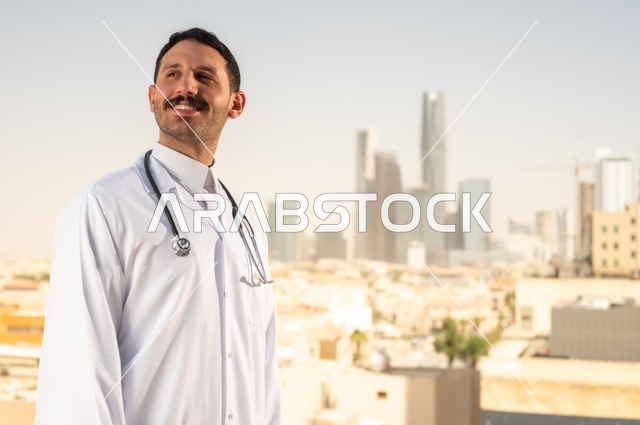مفهوم الفحص الطبي، العمل في القطاع الصحي، تقديم الخدمات العلاجية للمرضى, طبيب عربي خليجي سعودي يرتدي الثوب التقليدي والمعطف الطبي يضع السماعة الطبية يعمل في المراكز الصحية والمستشفيات، خلفية أبراج الرياض