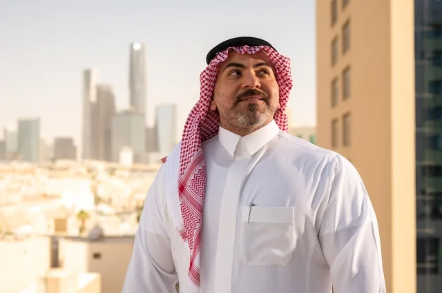 Pride and honor in the Saudi state, towers and skyscrapers of Riyadh, close-up of a Saudi Arabian Gulf man wearing the traditional thobe and shemagh standing straight with gestures of pleasure, progress and architectural development in the Gulf states