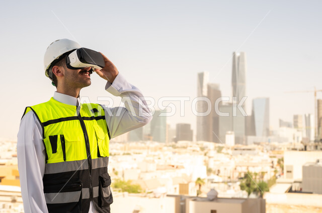 Viewing the engineering project plan via VR, Saudi national construction projects, interest in technology and urban development, a Saudi Gulf Arab engineer wearing a work jacket and white protective helmet studying the project using virtual reality glasses, integrating technology into architecture