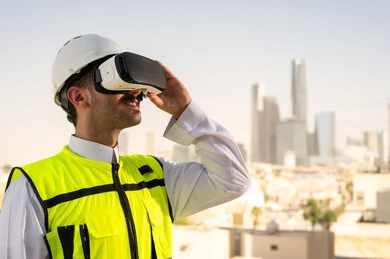 رؤية مخطط المشروع الهندسي عبر الفي الار, مشاريع إعمارية سعودية وطنية، الاهتمام بالتكنولوجيا والتطور العمراني, مهندس عربي خليجي سعودي يرتدي سترة العمل وخوذة الحماية البيضاء يقوم بدراسة المشروع باستخدام نظارة الواقع الافتراضي, دمج التقنية في الهندسة المعمارية