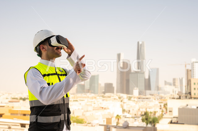 رؤية مخطط المشروع الهندسي عبر الفي الار, مشاريع إعمارية سعودية وطنية، الاهتمام بالتكنولوجيا والتطور العمراني, مهندس عربي خليجي سعودي يرتدي سترة العمل وخوذة الحماية البيضاء يقوم بدراسة المشروع باستخدام نظارة الواقع الافتراضي, دمج التقنية في الهندسة المعمارية