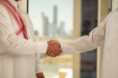 الشراكة في الأعمال والمشاريع الهندسية، صداقات وتعارف وبناء علاقات اجتماعية، عقد صفقات عمل جديدة ناجحة بين رجال الأعمال، صورة مقربة لايدي رجلين سعوديين عربيين خليجيين يرتديان الزي التقليدي يقومان بمصافحة بعضهما، توسيع مجالات العمل