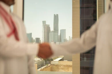 الشراكة في الأعمال والمشاريع الهندسية، صداقات وتعارف وبناء علاقات اجتماعية، عقد صفقات عمل جديدة ناجحة بين رجال الأعمال، صورة مقربة لايدي رجلين سعوديين عربيين خليجيين يرتديان الزي التقليدي يقومان بمصافحة بعضهما، توسيع مجالات العمل