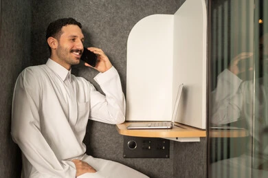 Making a call on a mobile phone, managing and organizing business affairs, using a modern and advanced technical device, an administrative office profession and job, a Saudi Arabian Gulf man wearing traditional clothing working on a laptop in the office, companies and offices in the Kingdom of Saudi Arabia