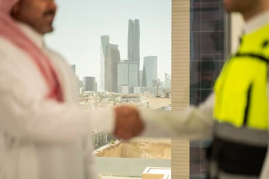 تعابير المصافحة والترحيب والاستقبال, مفهوم التعاون والعمل المشترك, صورة مقربة لايدي مهندس عربي خليجي سعودي يرتدي الخوذة وسترة الحماية يقوم بالتصافح مع رجل اعمال, الاتفاق على الخطط والمشاريع الهندسية في موقع العمل , الإنشاءات المعمارية في الأراضي السعودية