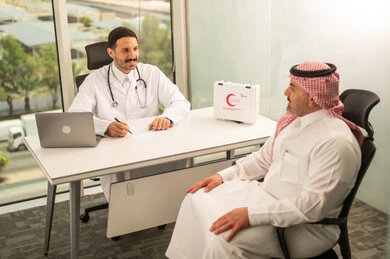 Recording patient cases on a computer, a Saudi Arabian Gulf doctor wearing a white coat explaining the medical condition of a patient wearing a traditional keffiyeh and thobe, dialogue with patients to determine the condition, providing consultations in medical centers, following up on the medical records of patients, working in the health sector