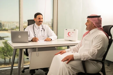  تسجيل حالات المرضى على جهاز الحاسوب, طبيب عربي خليجي سعودي يرتدي المعطف الأبيض يقوم بشرح الحالة المرضية لمريض يرتدي الشماغ والثوب التقليدي, الحوار مع المرضى لكشف الحالة، تقديم الاستشارات في المراكز الطبيه, متابعة السجل الطبي للمراجعين, العمل في القطاعات الصحية