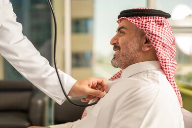 المتابعة الدورية لفحص نبضات القلب, طبيب عربي خليجي سعودي يرتدي المعطف الطبي يقوم باستخدام سماعه الفحص الطبية لمريض كبير بالسن, قياس  معدل ضربات القلب, مفهوم الطب والرعاية الصحية